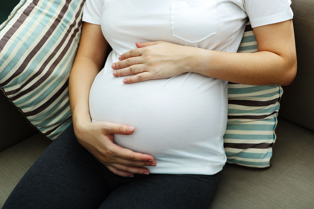 A pregnant birth mother sits on a couch